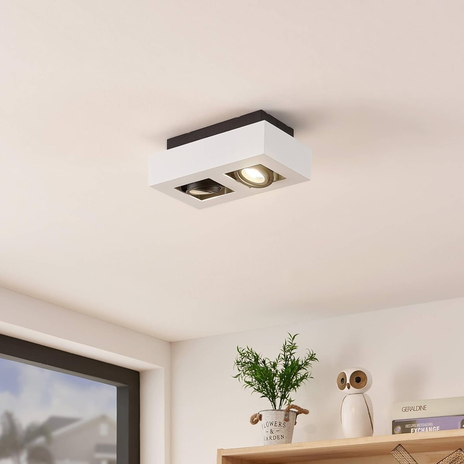 Image of the Arcchio VINCE ceiling lamp installed on a ceiling, with one light on and the other off, demonstrating its adjustable nature.