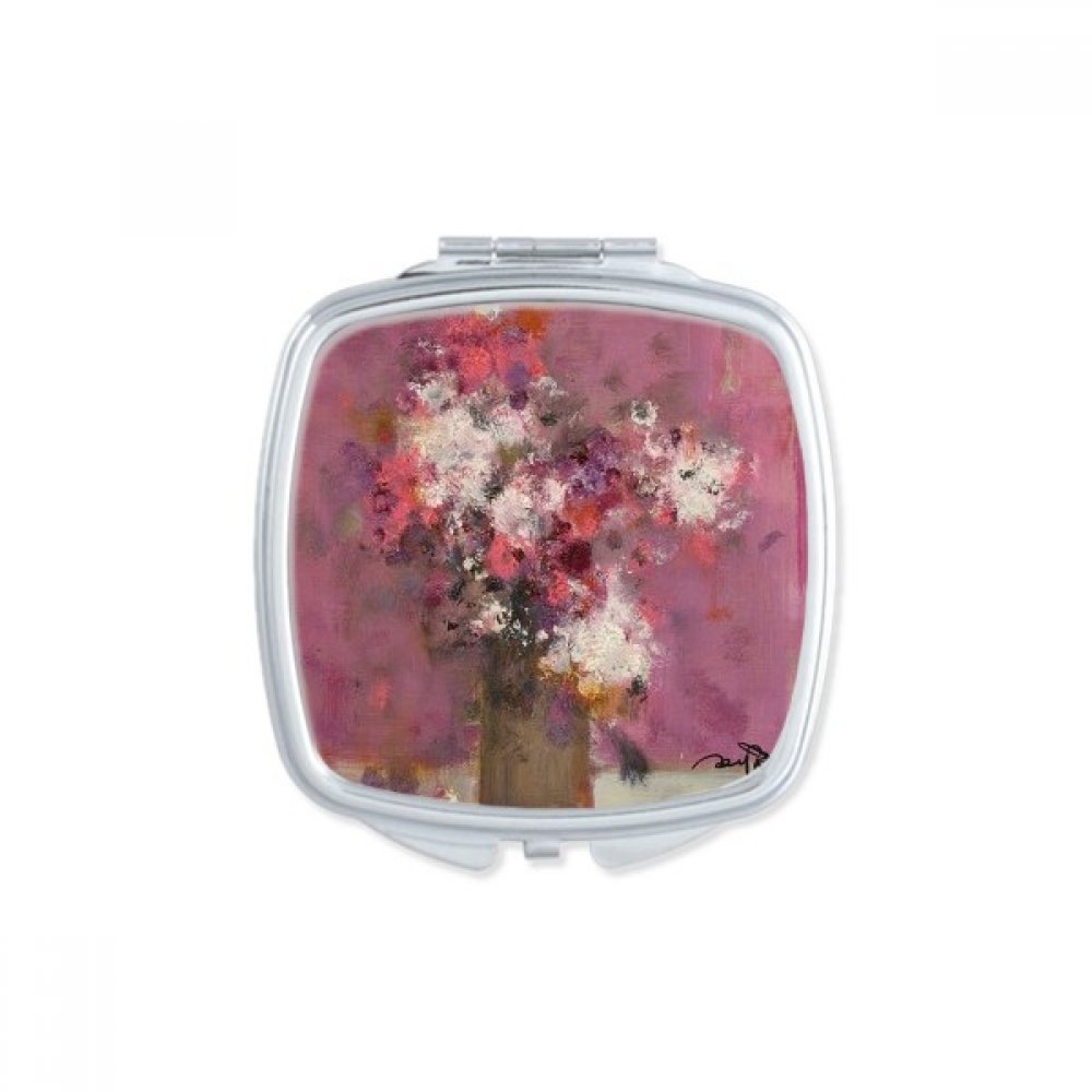 Miroir de poche à la main fleurs roses pour retouches maquillage en voyage