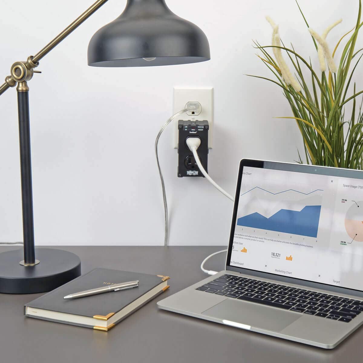 Tripp Lite Isobar ULTRABLOK in use on a desk, protecting a laptop and lamp