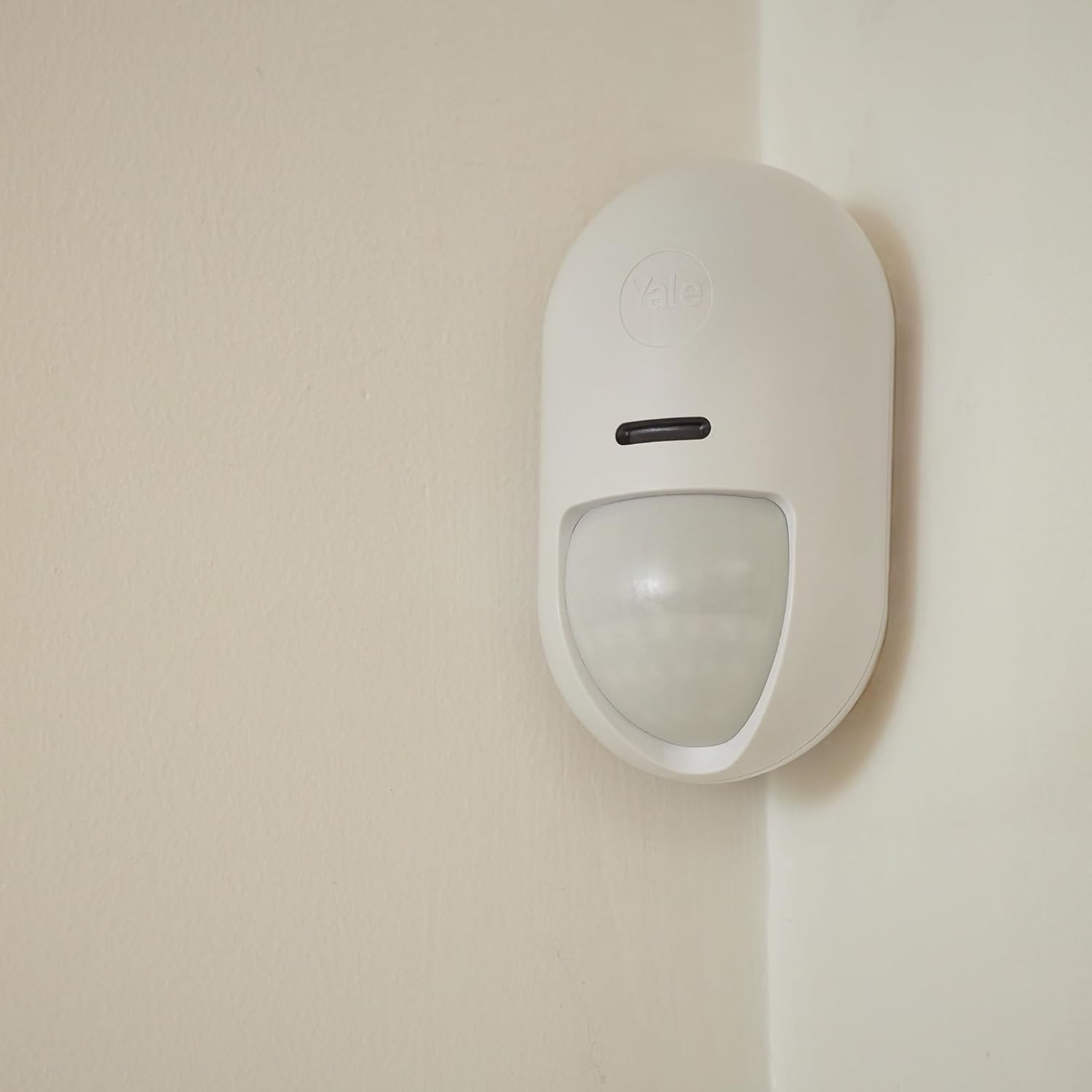 A Yale motion sensor mounted in the corner of a room.