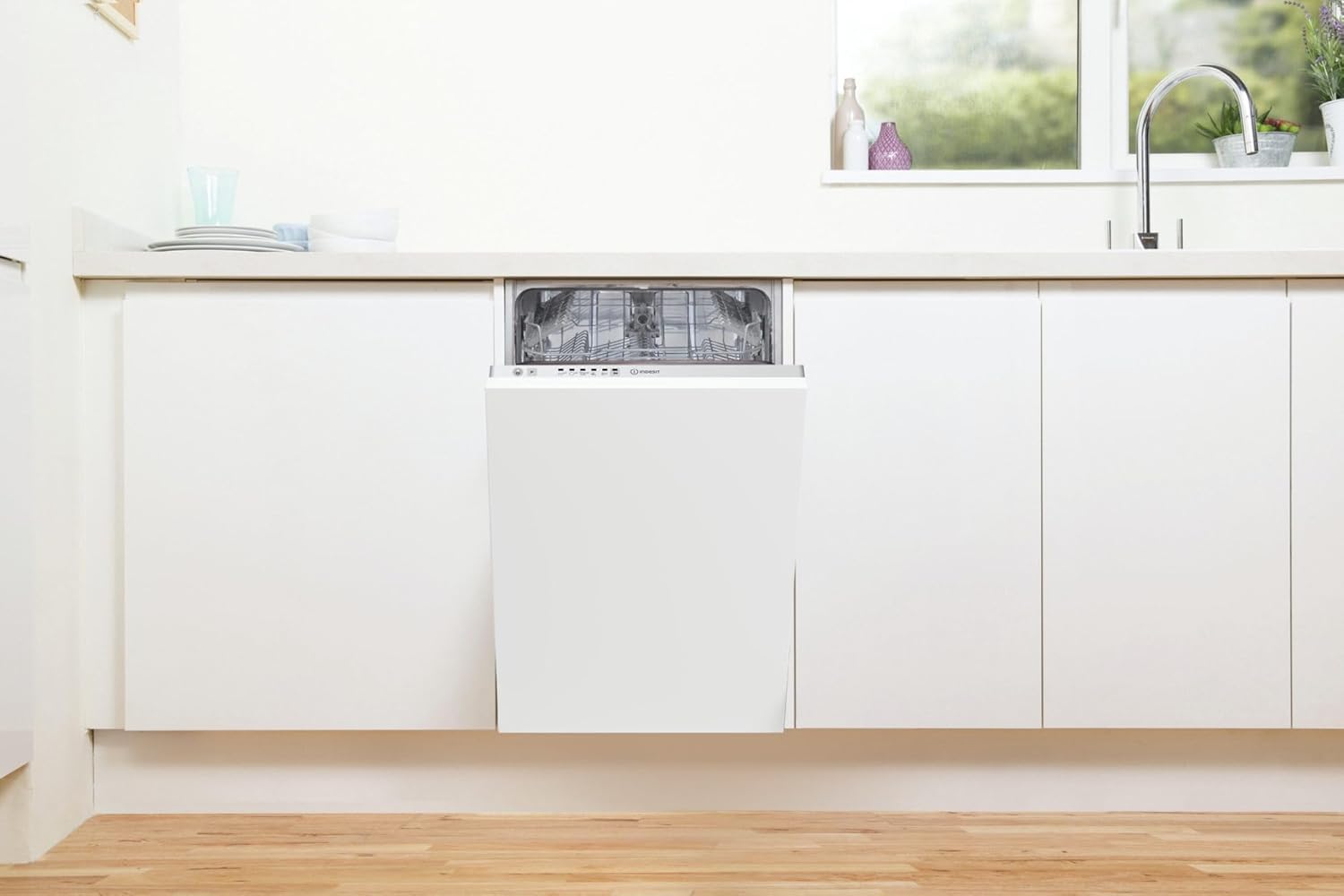 Indesit DI9E 2B10 dishwasher integrated into a modern kitchen, door slightly ajar.