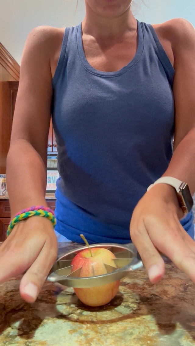 Positioning the apple wedger over an apple on a cutting board.