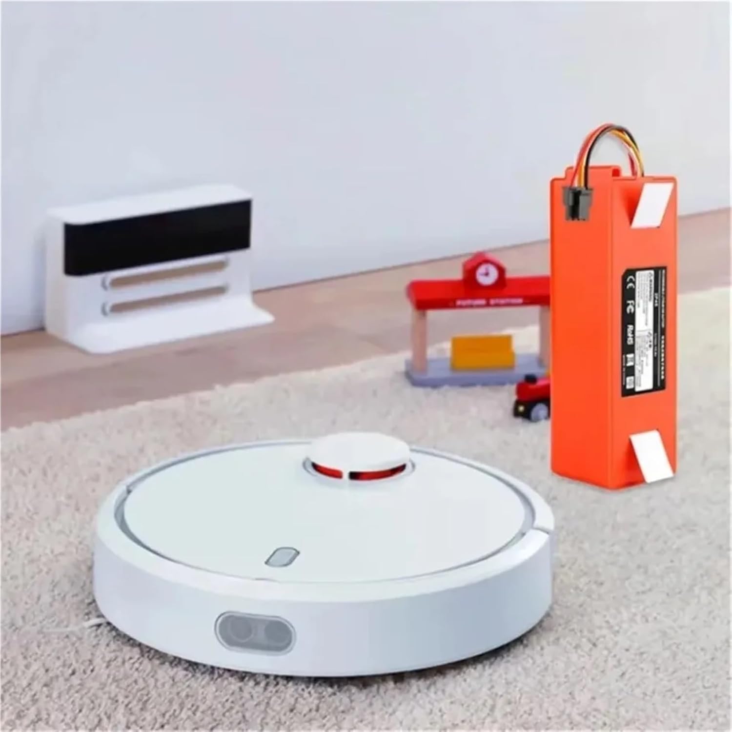 FGJDFD replacement battery next to a Xiaomi Roborock robot vacuum