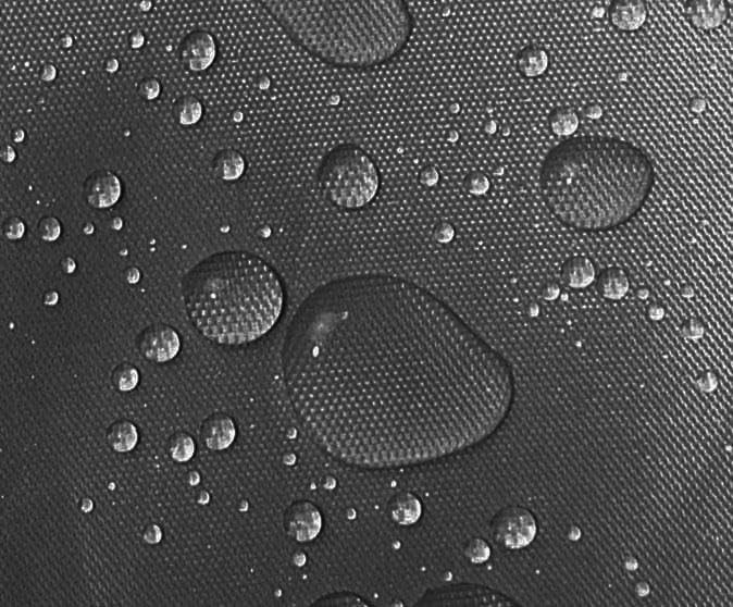 Close-up of water beads on the black fabric of the cover, demonstrating its water-resistant properties.