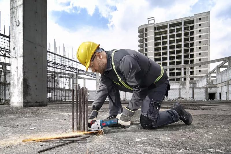 Worker using BOSCH angle grinder to cut rebar on a construction site