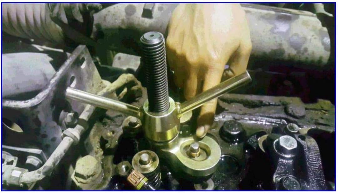 Valve spring compressor tool in use on an engine cylinder head