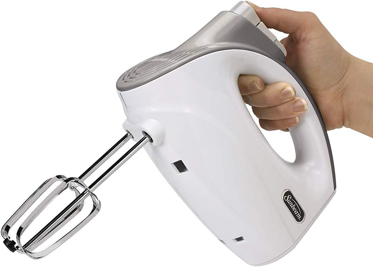A hand holding the Sunbeam Mixmaster handheld unit with beaters attached.