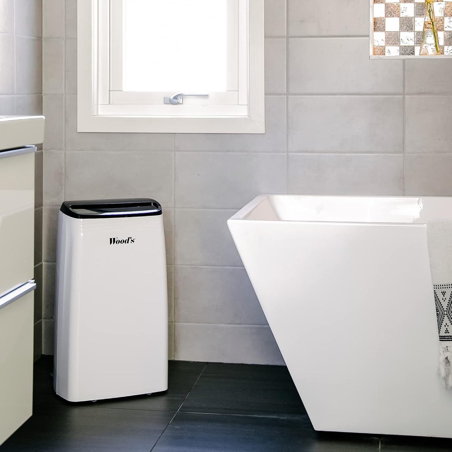 Wood's MDK 21 Dehumidifier placed in a modern bathroom next to a white bathtub.