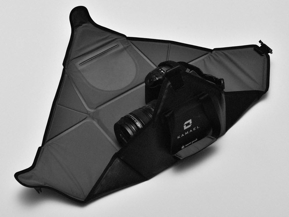 Snow Peak Kamae Mat Bag partially folded around an SLR camera, demonstrating its protective enclosure.