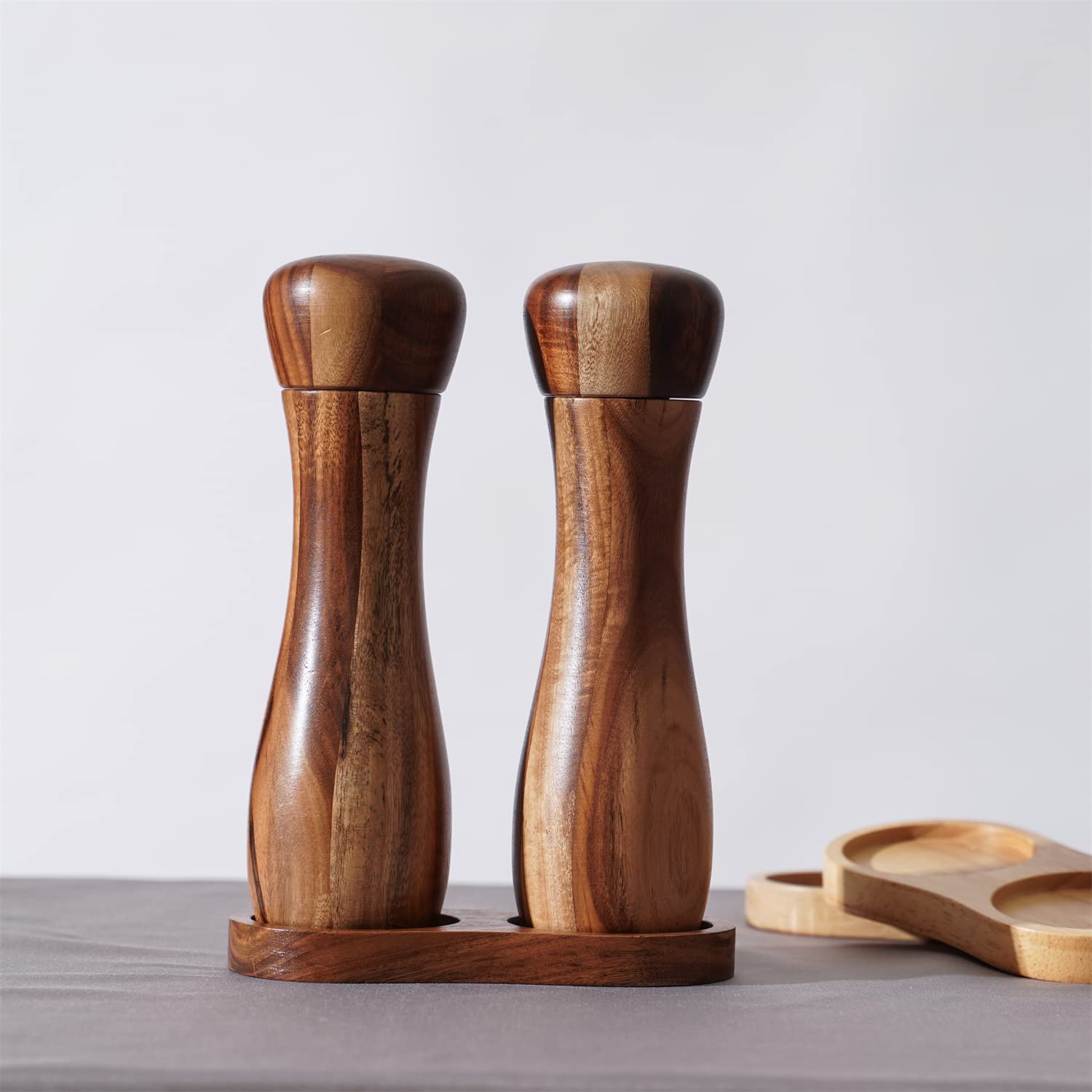 Zestaw młynków do soli i pieprzu DeroTeno wraz z podstawką. Dwa młynki do soli i pieprzu z ceramicznym mechanizmem mielenia. Drewno akacjowe, wysokość 20,5 cm, średnica 6 cm.