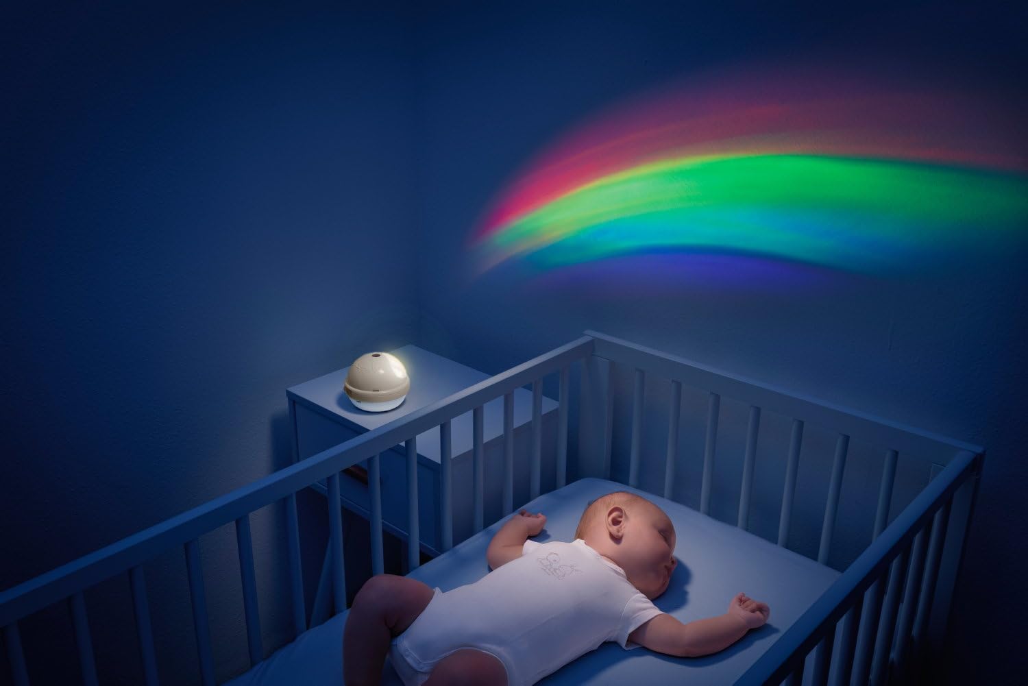Baby in cot with Chicco projector unit on bedside table