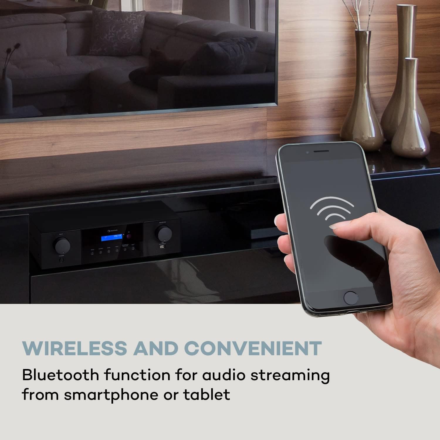 A hand holding a smartphone streaming music wirelessly to the Auna AMP-4000 DAB ampmés viu.