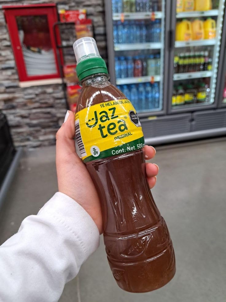 A hand holding a single bottle of JAZ TEA Original Iced Tea
