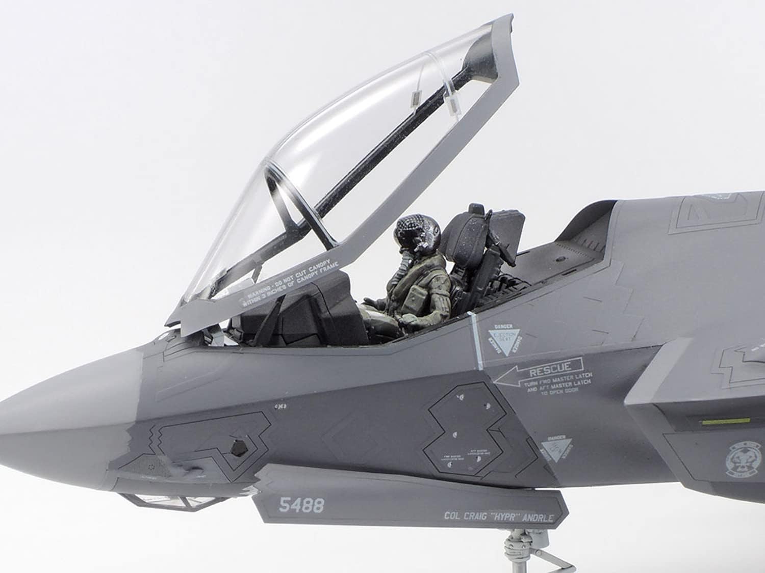 Close-up of the F-35A cockpit with a pilot figure seated, canopy open.