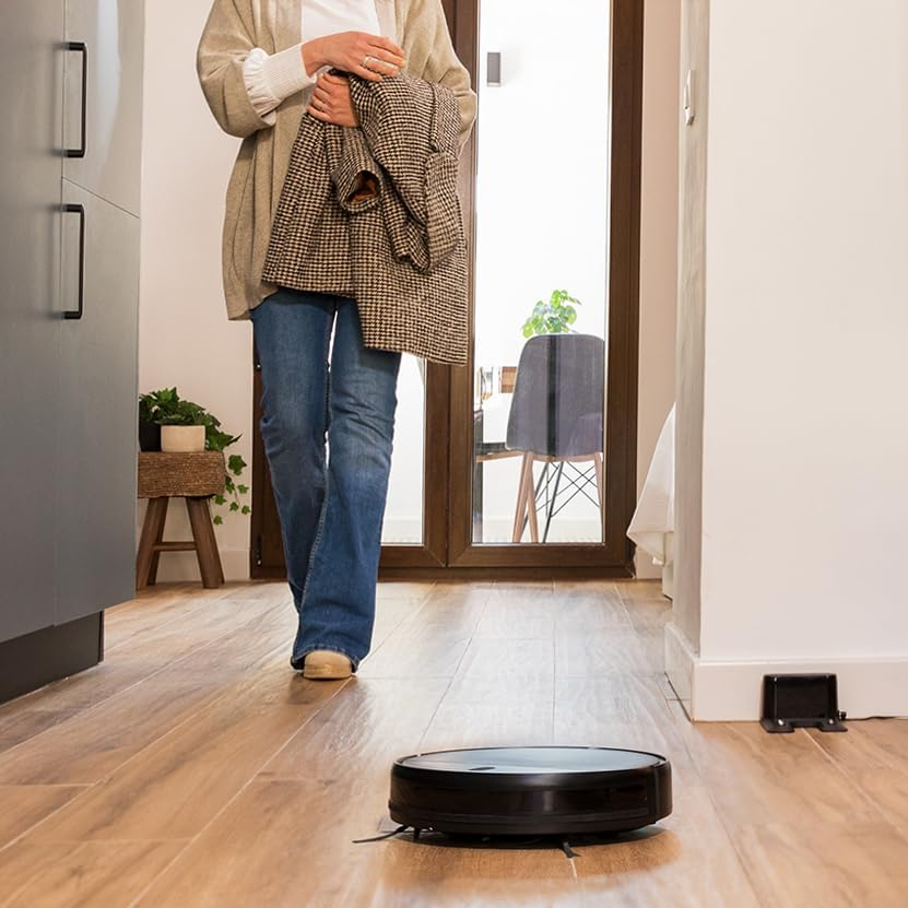 Cecotec Conga M10 robot vacuum cleaner moving across a wooden floor in a hallway.