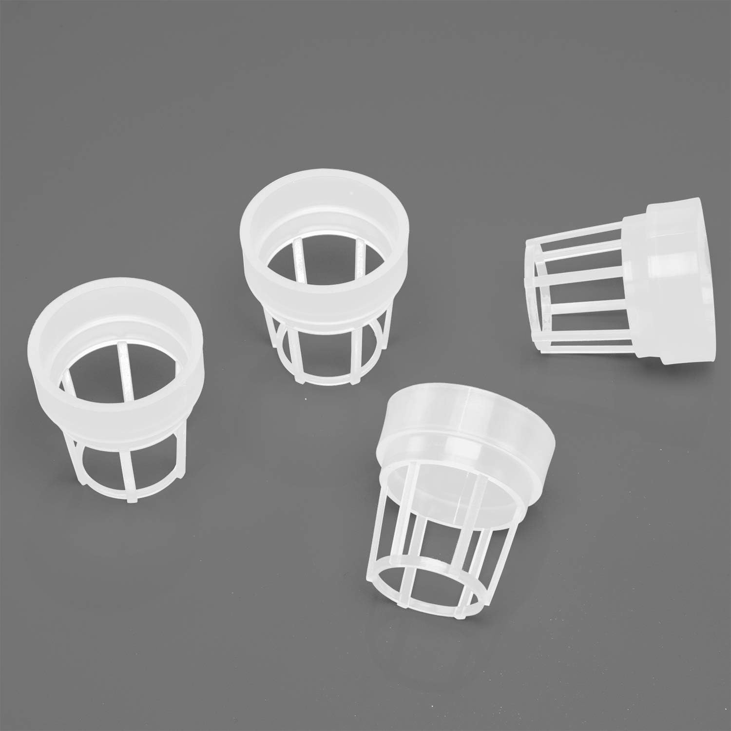 Four white slotted growing baskets on a grey background