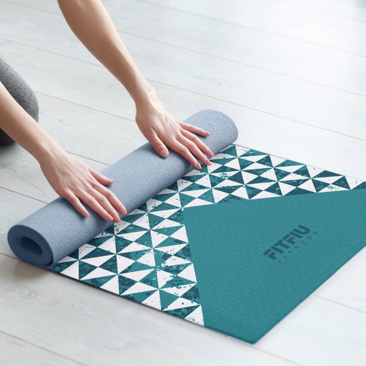 Person rolling out a Fitfiu Fitness yoga mat with a geometric pattern