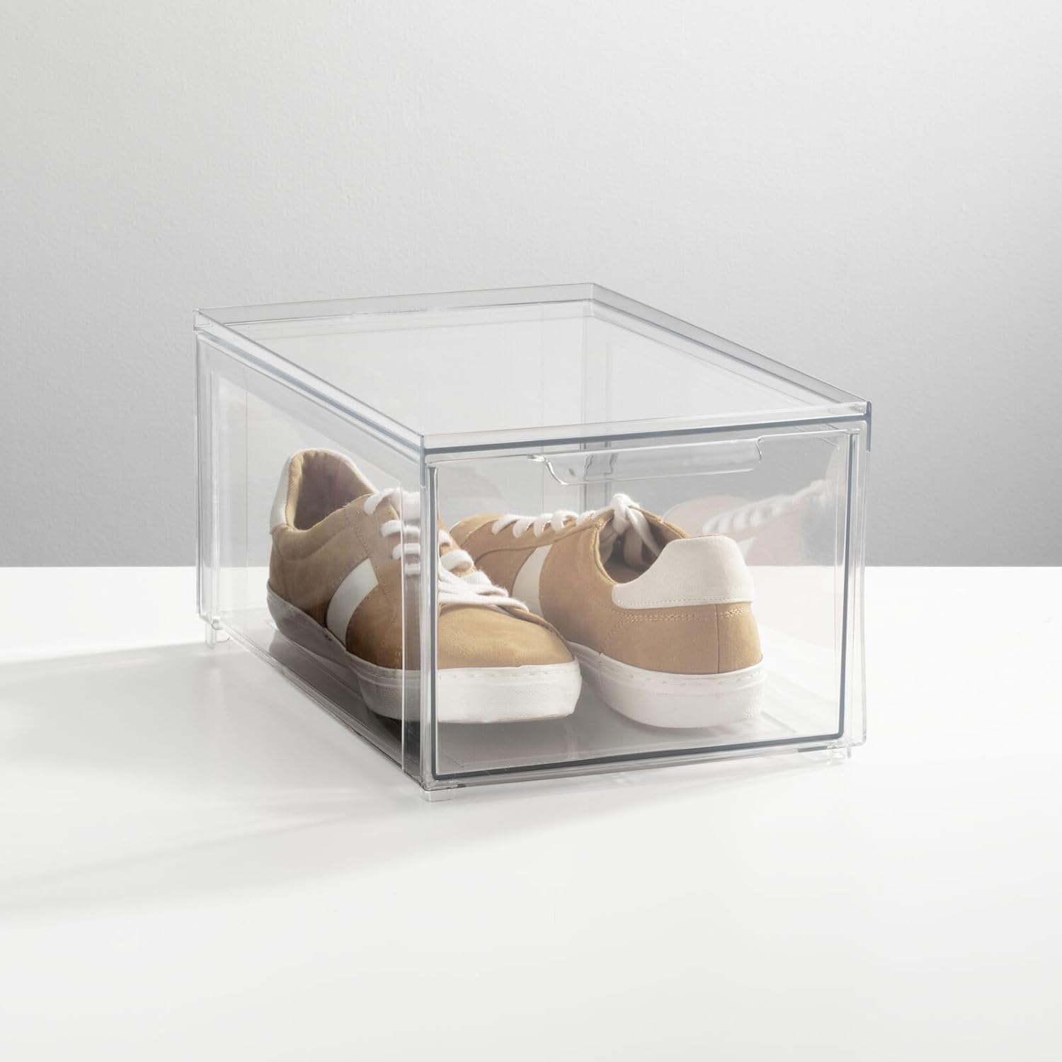 A single clear storage bin containing a pair of light-colored sneakers