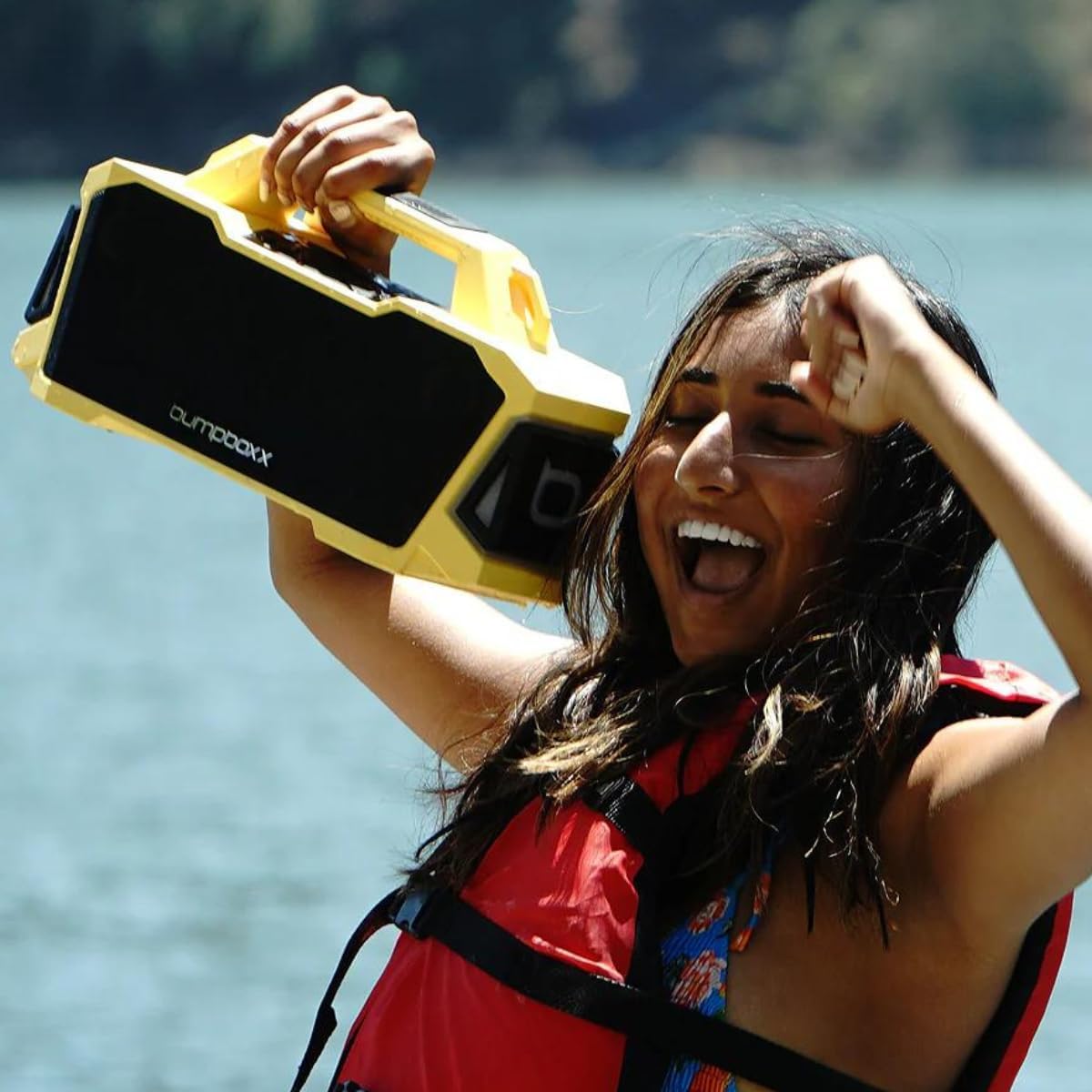 Person happily holding a yellow Bumpboxx Thump speaker outdoors