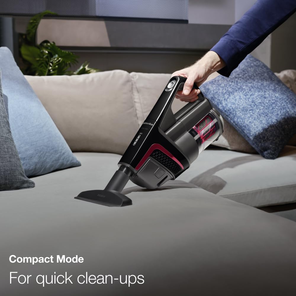 A person using the Miele Triflex HX1 in Compact Mode, cleaning upholstery with the handheld unit.