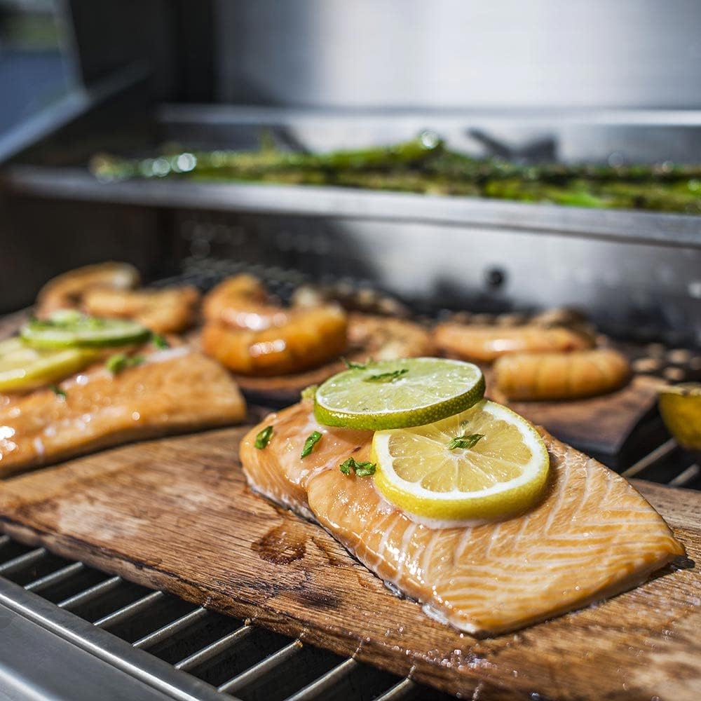 Food cooking on the grill, including salmon with lemon and lime slices