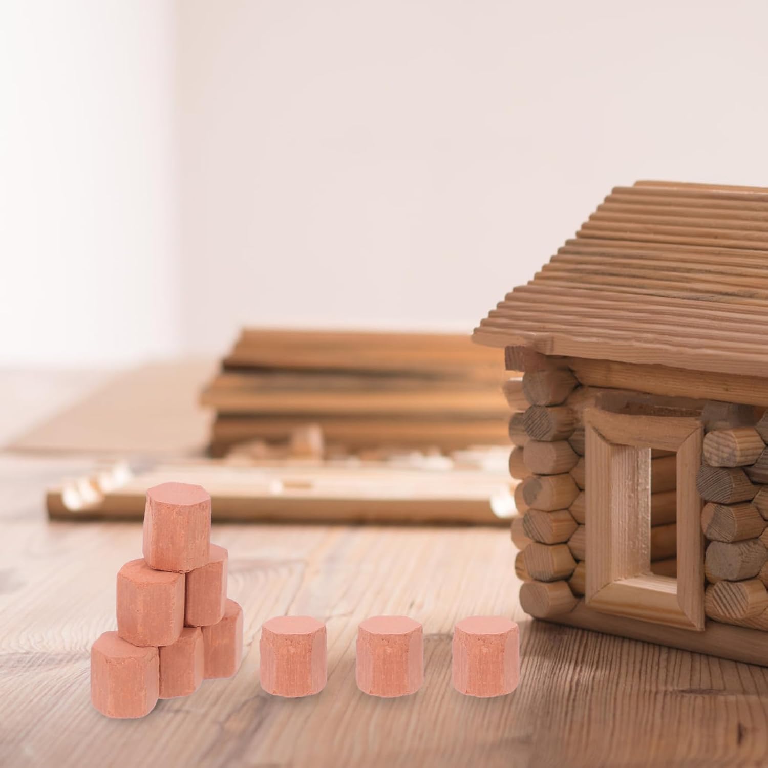 Several miniature bricks stacked next to a small wooden model house.