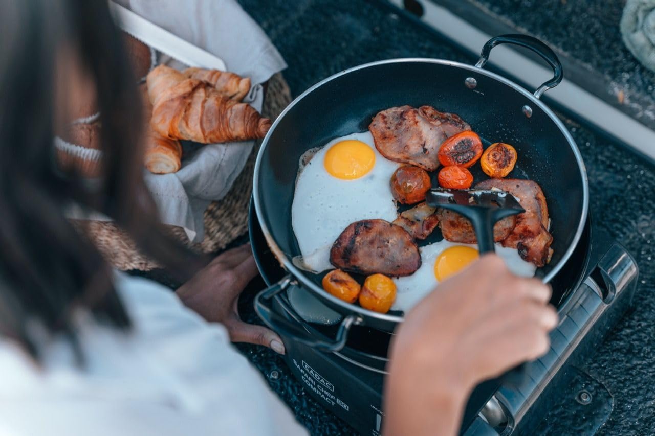 Person cooking eggs and bacon in a pan on the Cadac Safari Chef 30 using the pot stand.