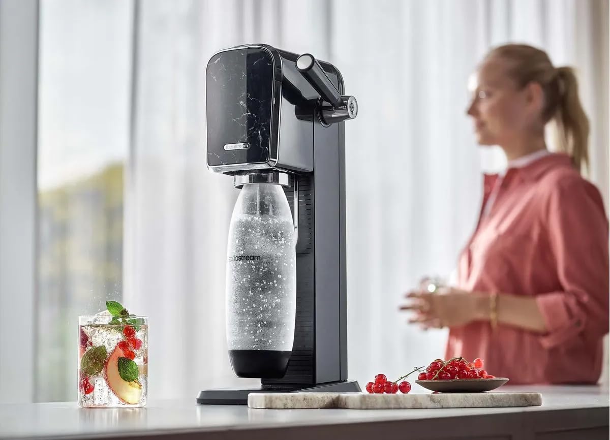 sodastream ART MARBLE in use, with a glass of sparkling water and fruit