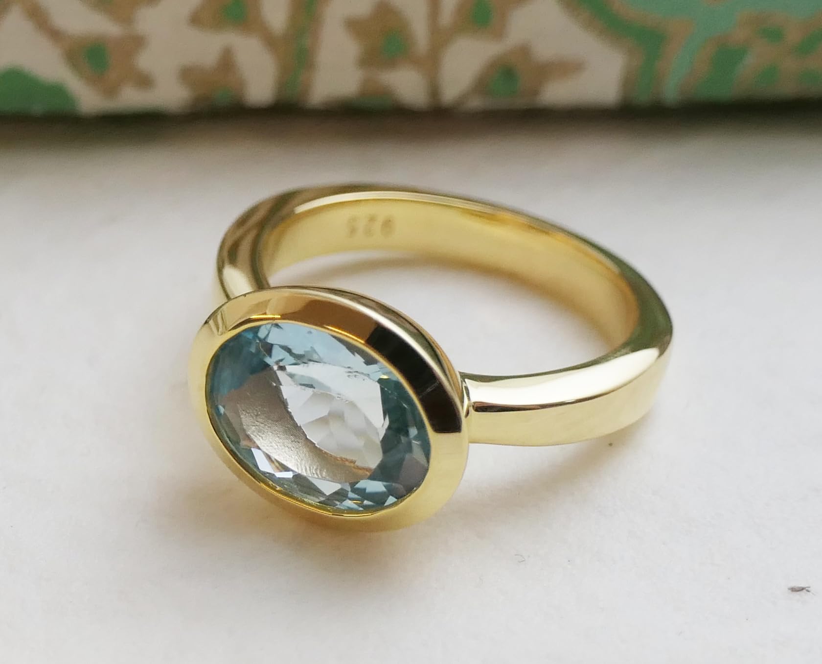 Anillo ovalado de plata de ley con baño de oro y topacio azul