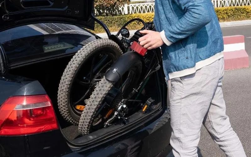 Person placing folded KOOLUX BK6 electric bike into a car boot