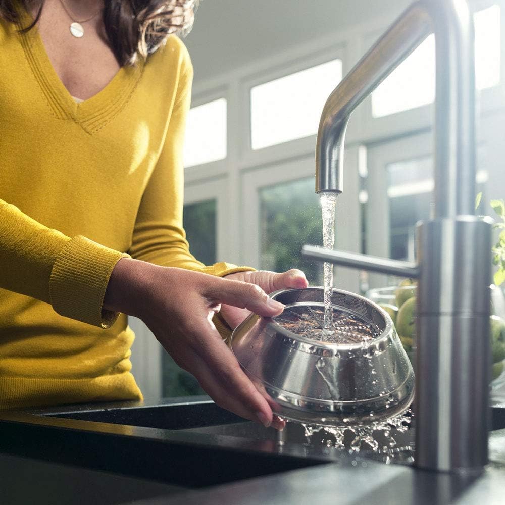 Woman cleaning juicer filter under tap