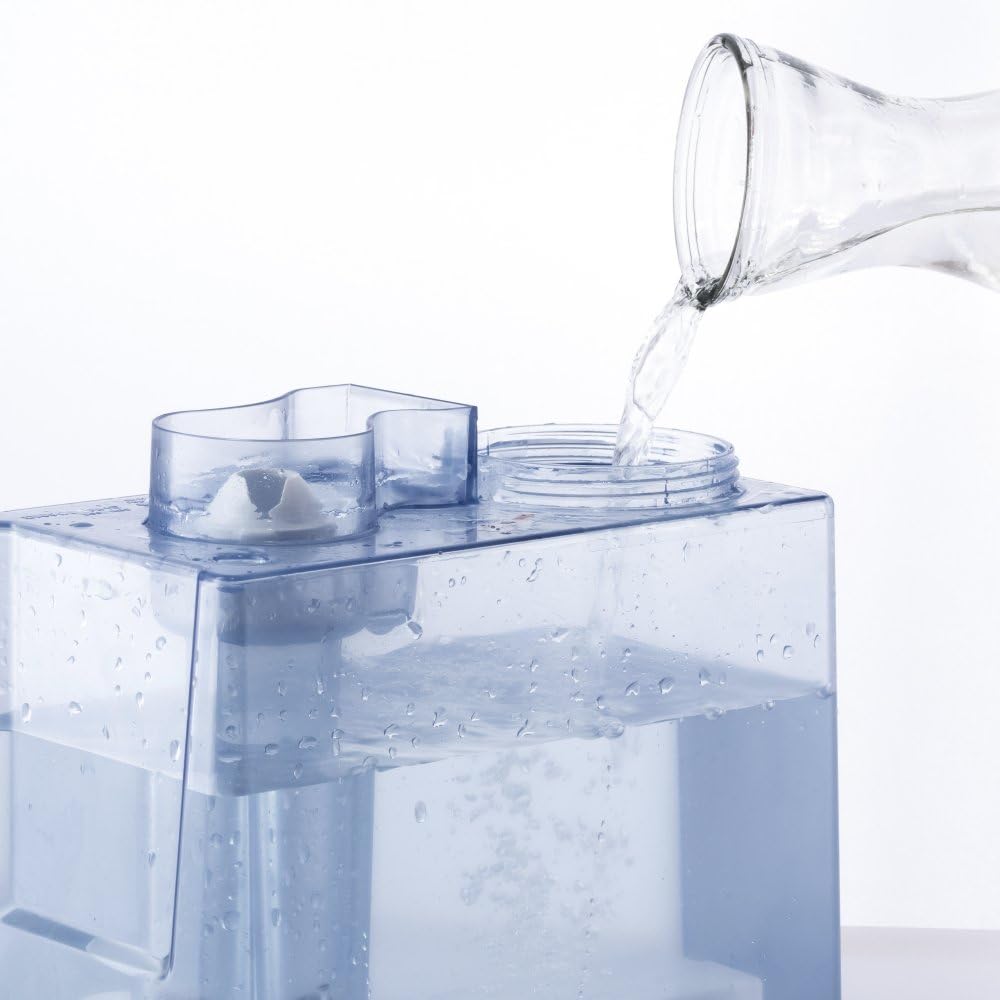 Hand pouring water into the transparent water tank of the TROTEC B 5 E humidifier.
