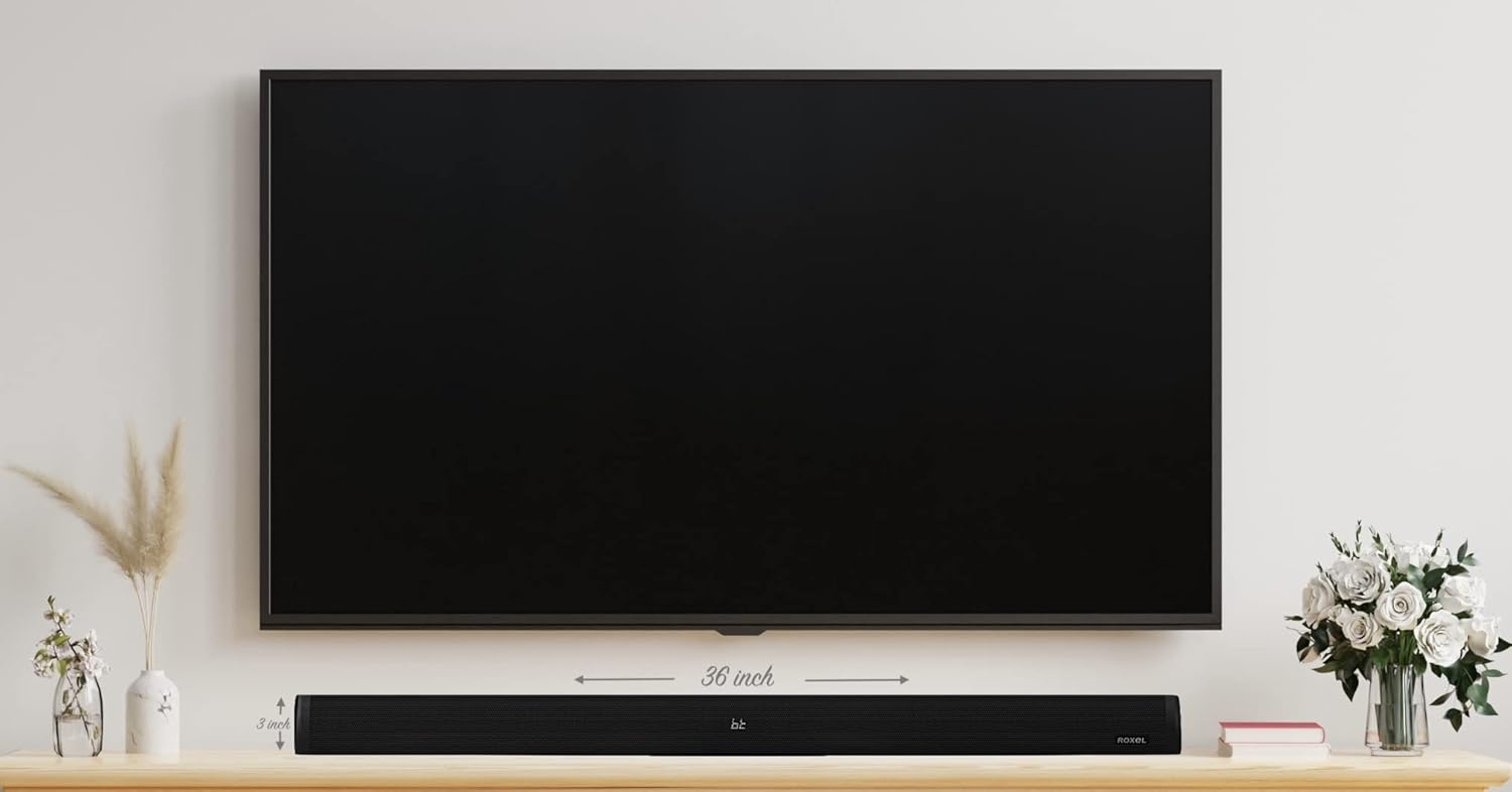 Roxel RSB500 Sound Bar placed on a TV stand below a television, showing its dimensions.