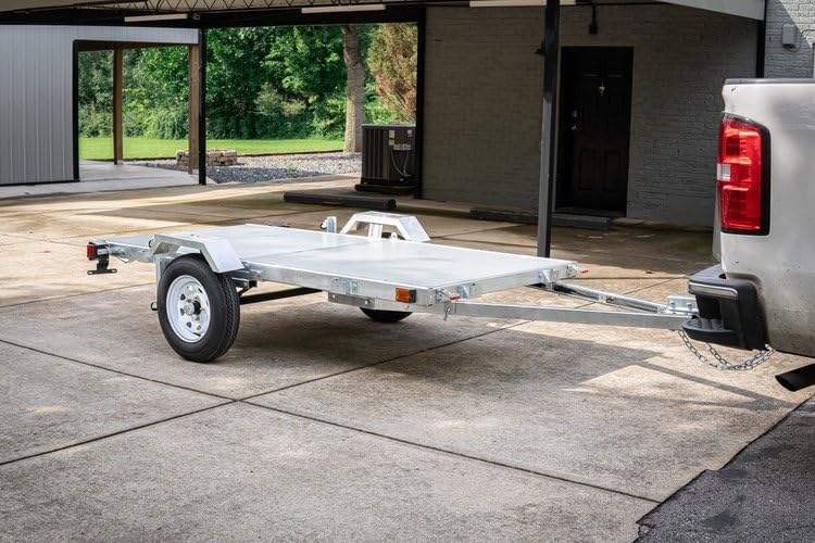 DK2 MFT4X8G trailer hitched to a pickup truck, viewபக்கத்தில் இருந்து ed.