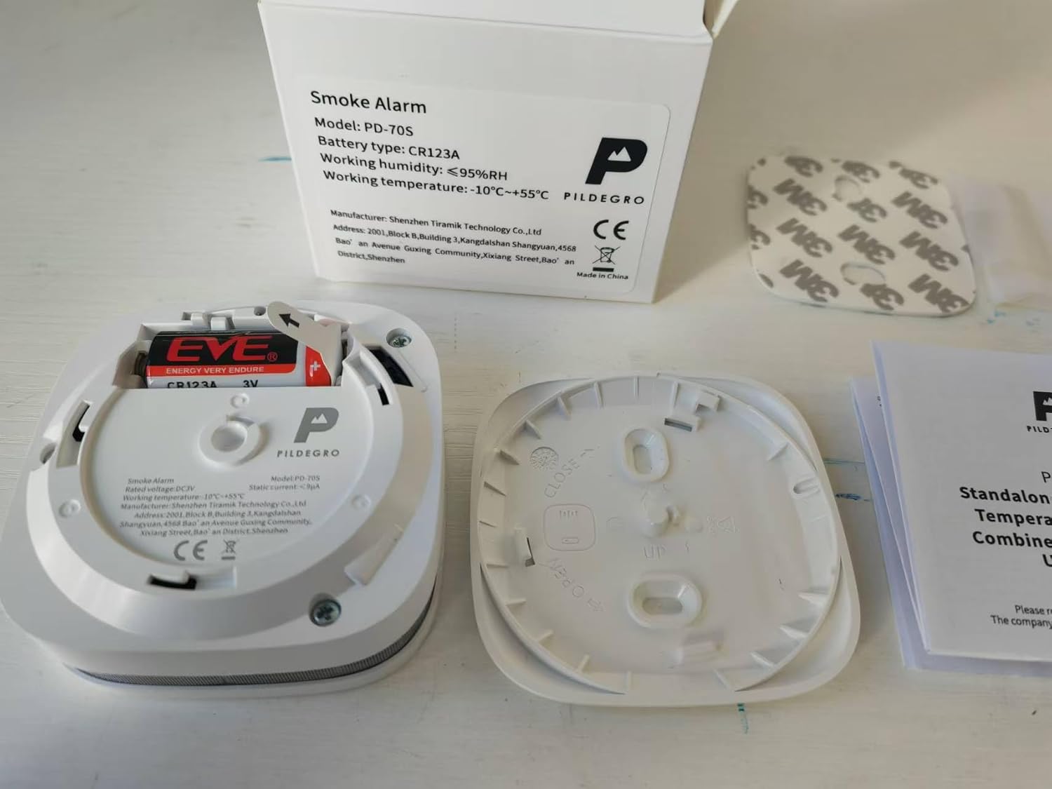 Back of the Pildegro PD-70S smoke detector with the battery compartment open, showing the CR123A battery and insulation tab.