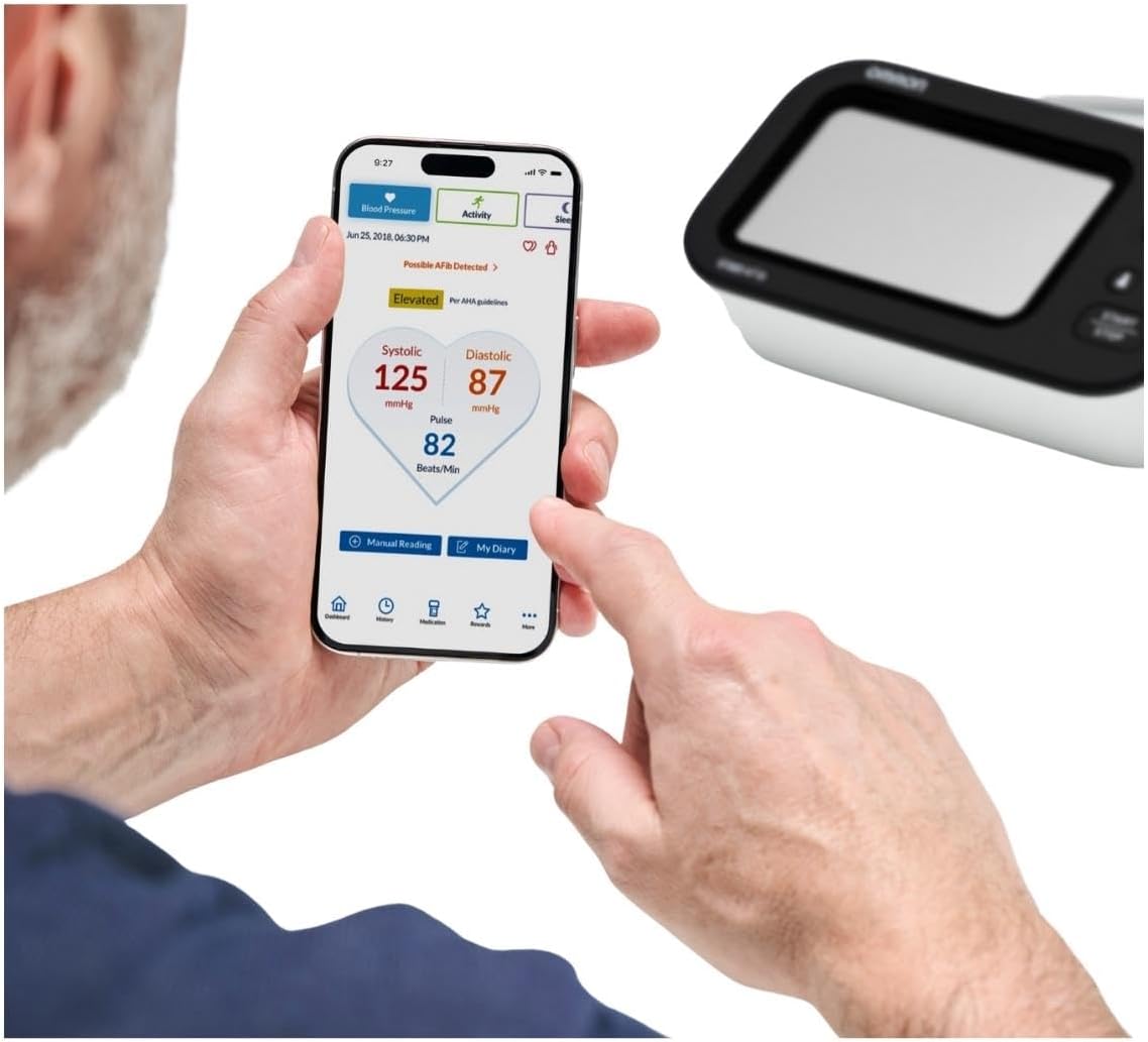 Person viewing Omron Connect app on smartphone with blood pressure monitor in background