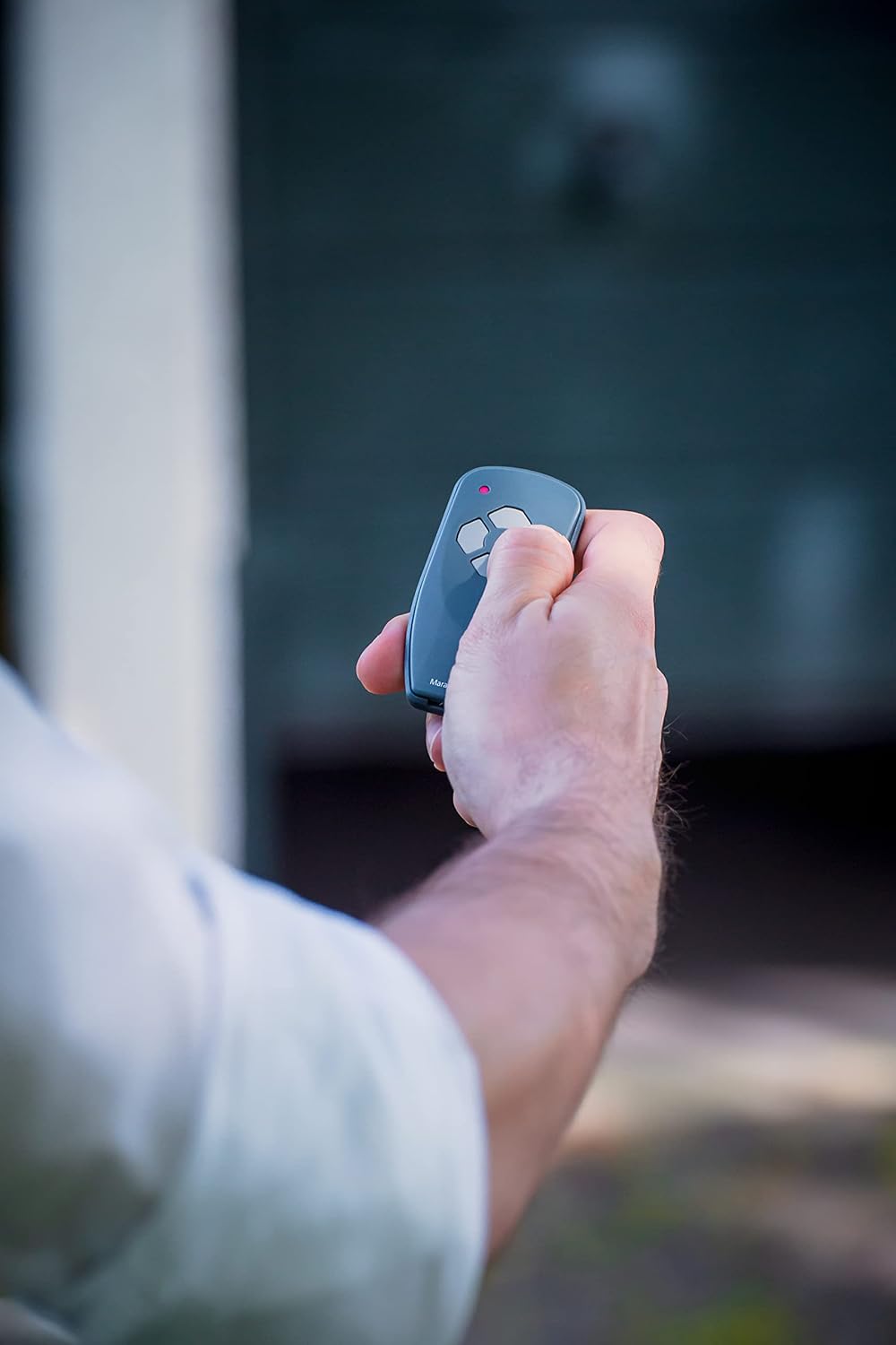 Hand holding the MARANTEC 122459 remote control, pressing a button