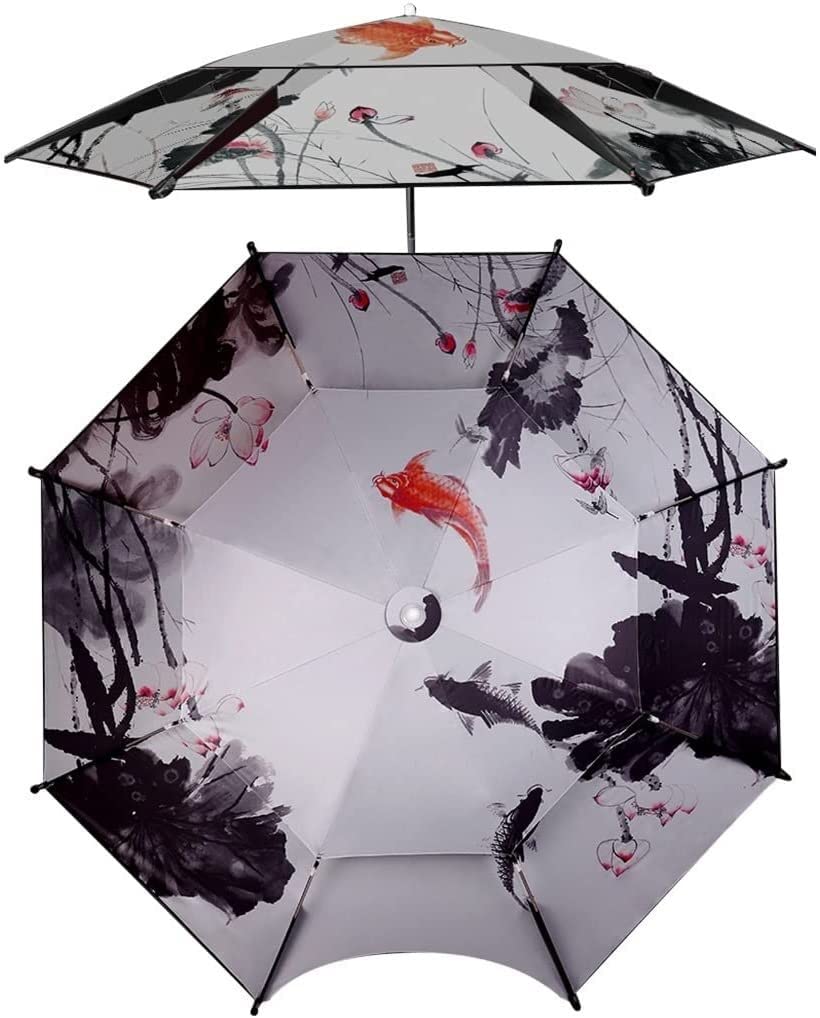 An outdoor scene showing a person seated under the MDybf fishing umbrella, which features an ink koi and lotus design, providing shade over water.