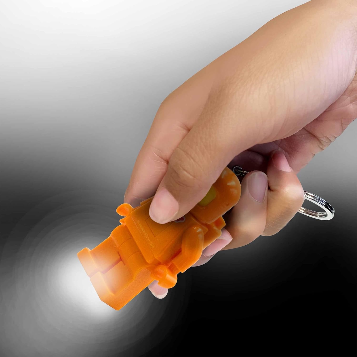 Hand holding LEGO Spaceman Keychain Light with LED lights on