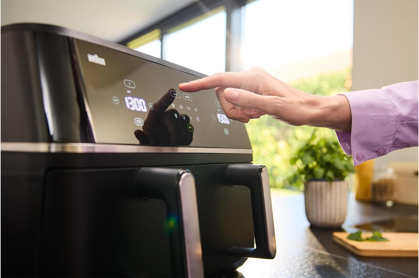 Close-up of a hand interacting with the touch control panel of the air fryer.