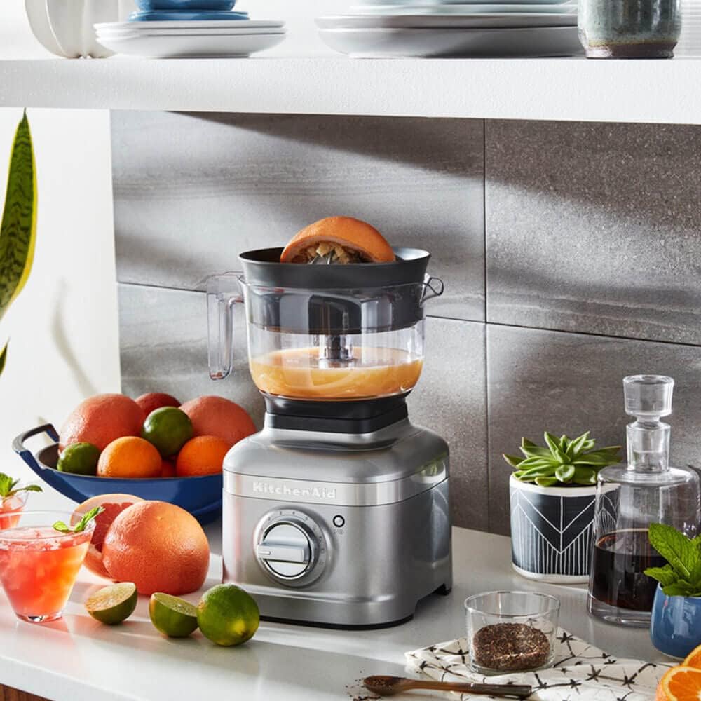 KitchenAid 5KSB1CPA Citrus Juicer Attachment in use on a silver KitchenAid blender, juicing a grapefruit