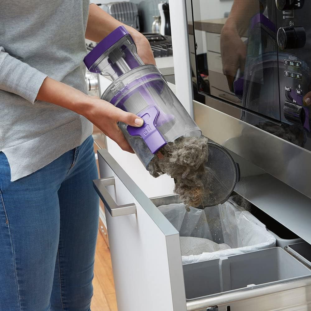 Woman using the BLACK+DECKER handheld vacuum with brush attachment on a sofa cushion