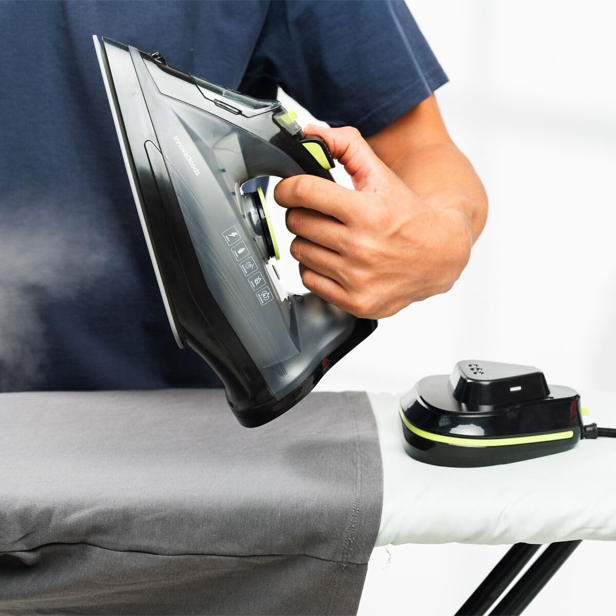 Person holding the InnovaGoods Stiron iron above a grey garment on an ironing board, demonstrating cordless use