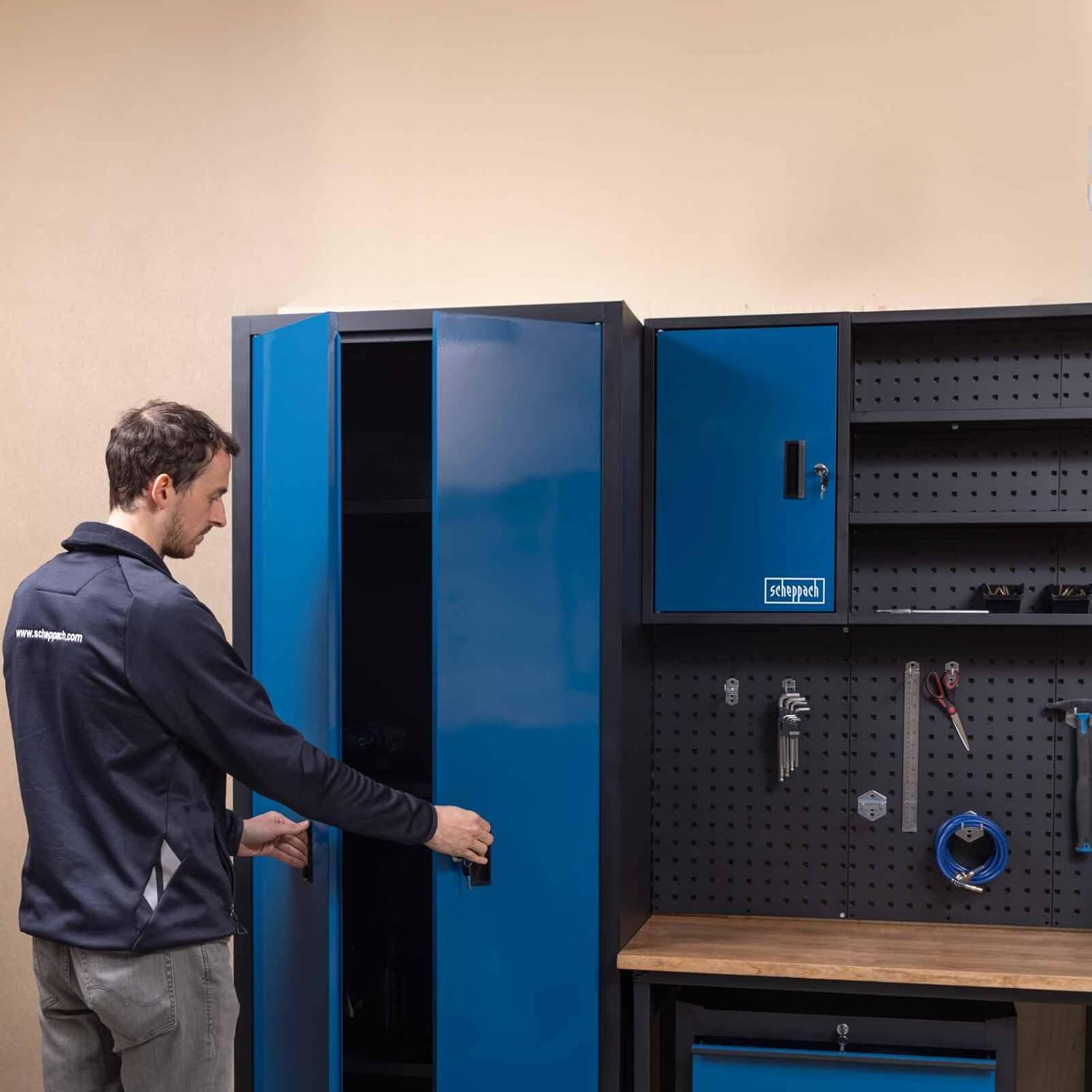 Person opening the tall blue Scheppach cabinet, part of the workshop system.