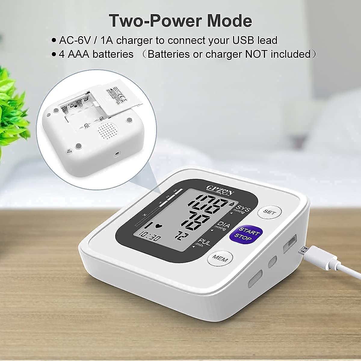 Back view of the GPZON Blood Pressure Monitor showing the battery compartment and a USB cable connected to the side.
