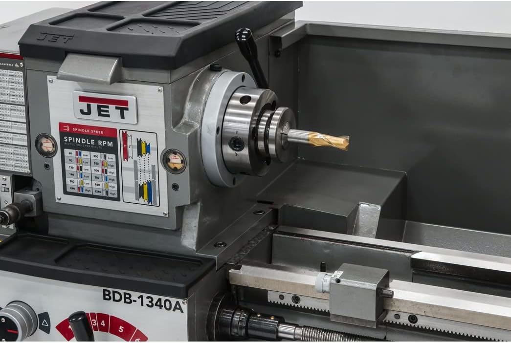 Fèmen view of the lathe's headstock, showing the spindle with a mounted chuck and a cutting tool in position.