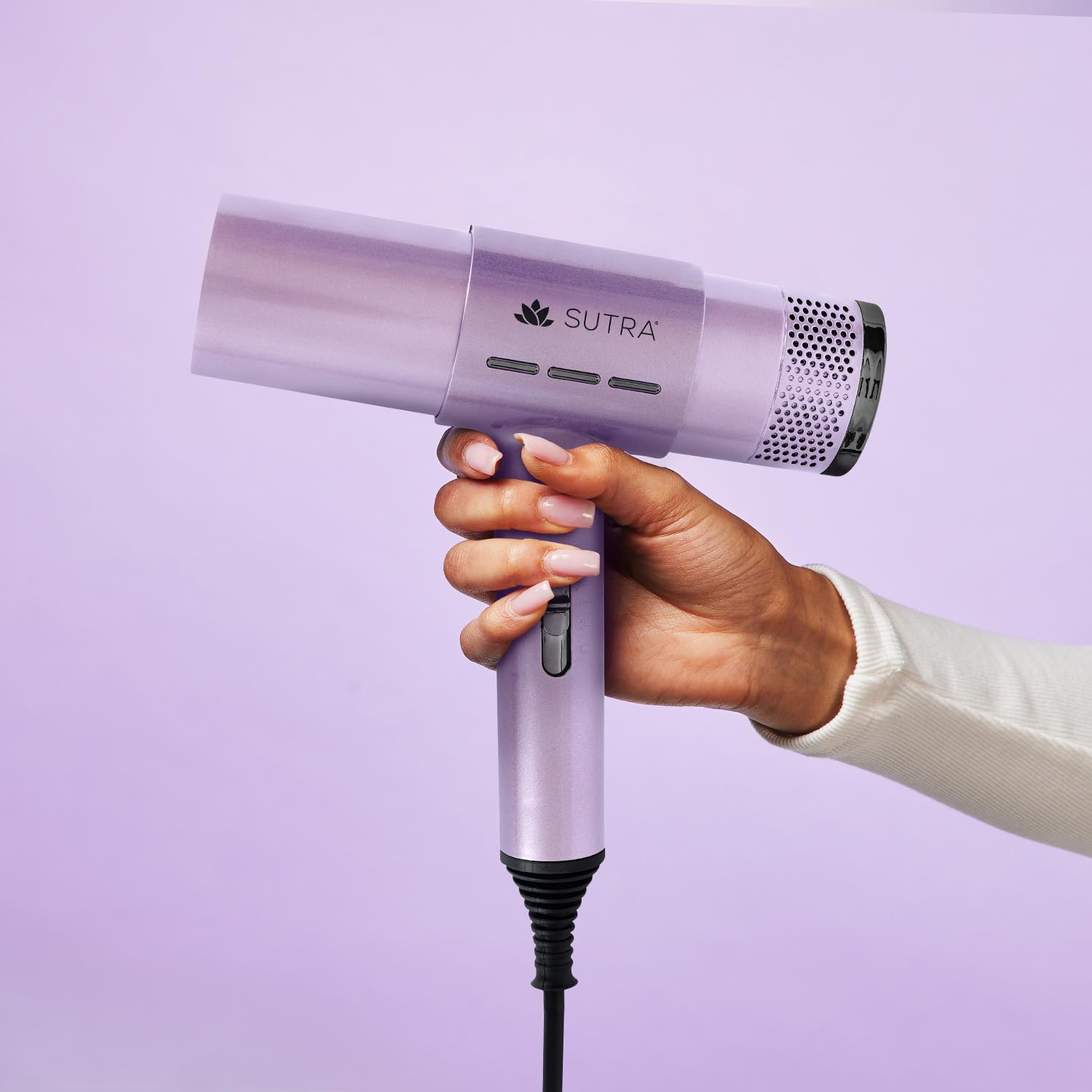 A hand holding the SUTRA Airpro Blow Dryer, demonstrating its ergonomic design