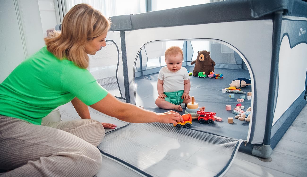 Adult interacting with a baby through the open zippered entrance of the Lionelo WILLOW XL playpen.