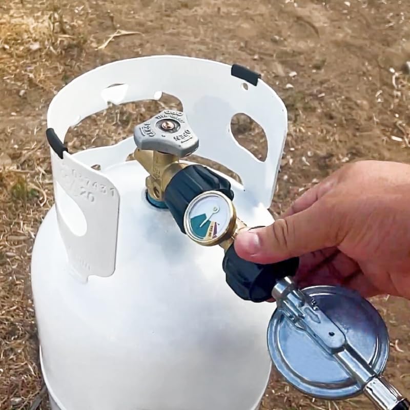 A hand tightening the Flame King YSN-212 Propane Gauge to a propane tank, with a regulator already attached to the gauge.