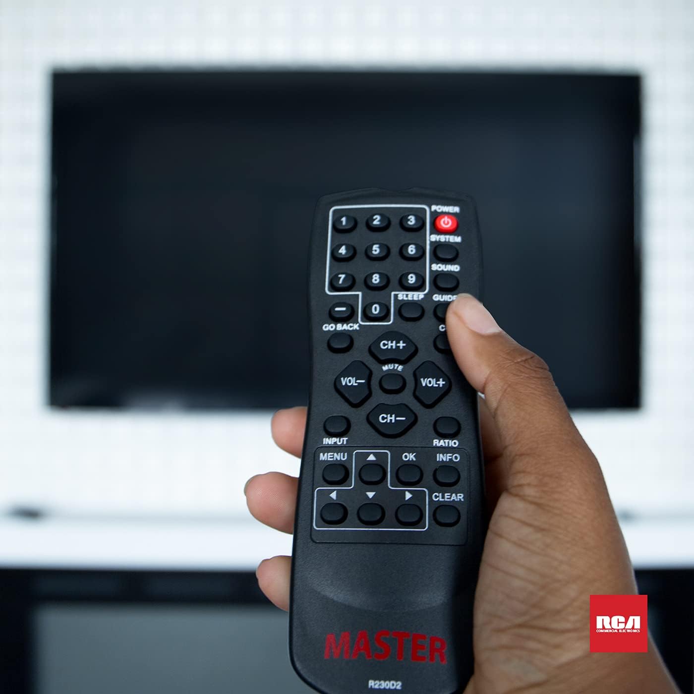 Hand holding the R230D2 Master TV Remote in front of a television